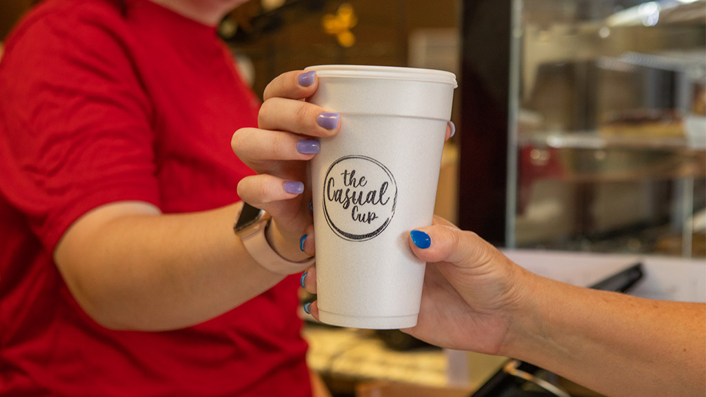 Employee passing a freshly brewed coffee to a customer